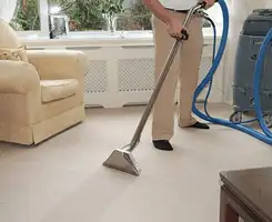 Carpet cleaning professional removing dirt and stains with a hot-water extraction tool in a home, Baltimore, MD.