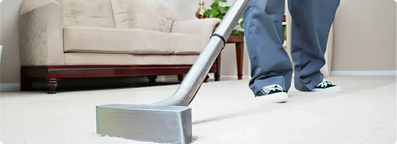 Carpet cleaning technician using a hot-water extraction wand on a light-colored carpet in a living room, Baltimore, MD.