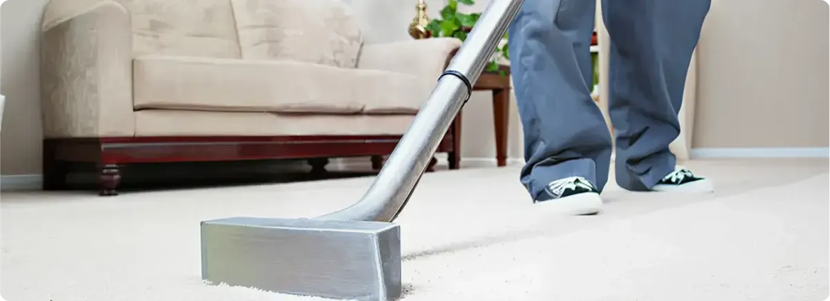 Carpet cleaning technician using a hot-water extraction wand on a light-colored carpet in a living room, Baltimore, MD.